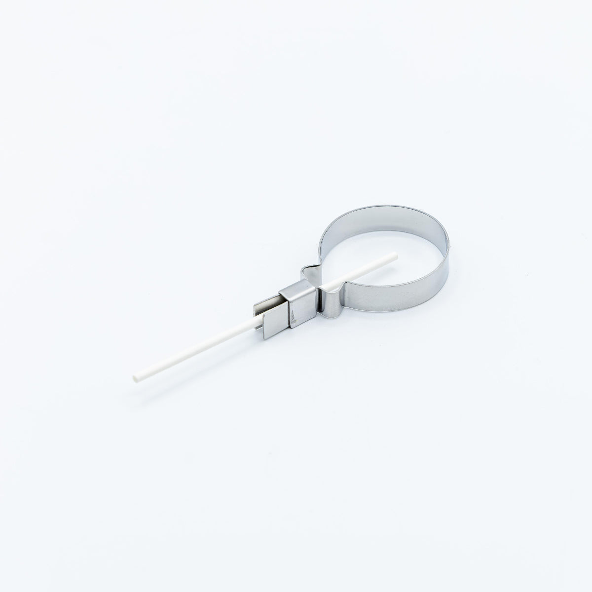 A silver metal lollipop mold with a white stick inserted through it, photographed on a clean white background.